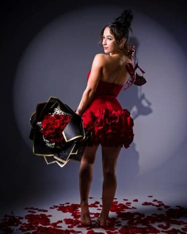 The shot: model in a red dress holding roses under a spotlight