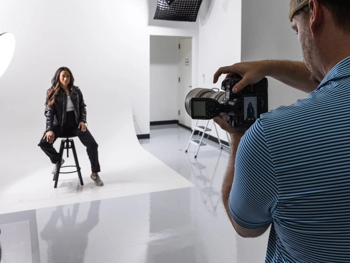 A photographer shooting a seated portrait on the white cyclorama